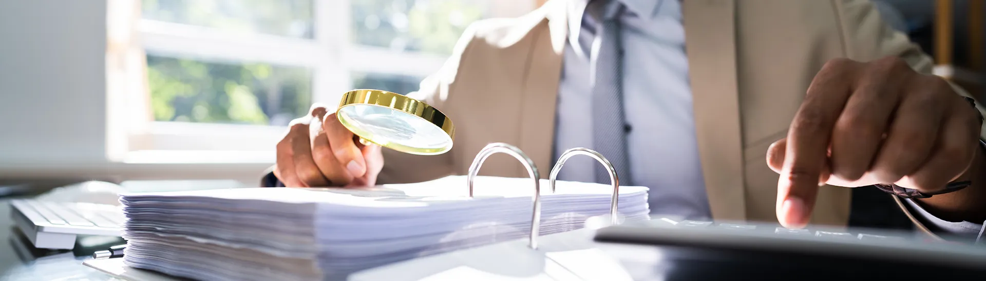 African American man reviewing a binder with a magnifying glass